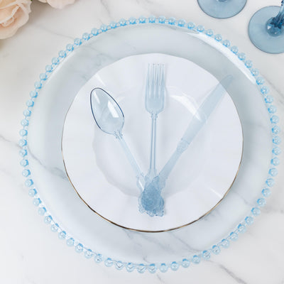 Elegant blue cutlery set on a decorative plate with pearl-like trim.