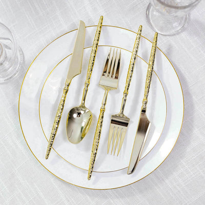 Gold hammered flatware set on white gold-rimmed dinner plates
