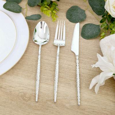 Elegant silver cutlery set with textured handles on a floral table setting