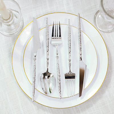 Elegant silver flatware set on white and gold-rimmed dinner plate