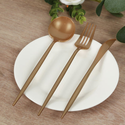 Gold cutlery set on a white plate with a wooden background.