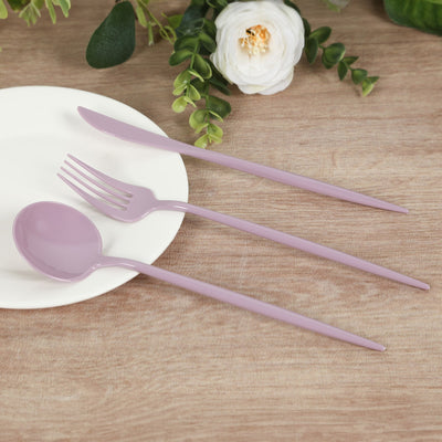 Purple plastic cutlery set on a wooden table with flowers.