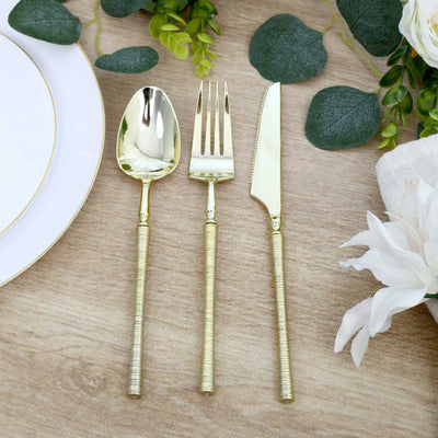 Gold flatware set with spoon, fork, and knife on a styled table setting