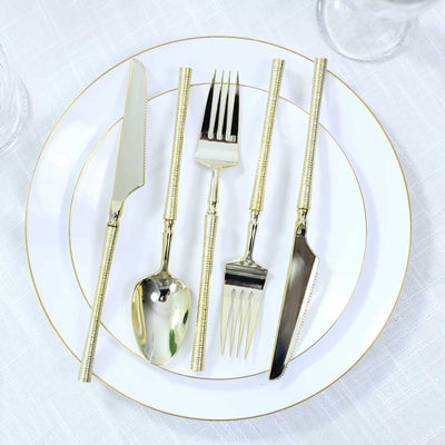Gold flatware set on white plate with gold trim, elegant table setting