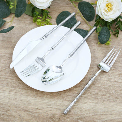 Silver rope-handle flatware set with fork, spoon, and knife on white plate