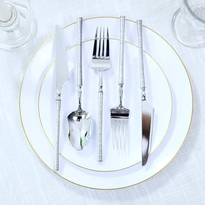 Elegant silver flatware set on white and gold-rimmed dinner plates