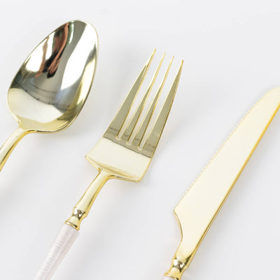 Gold flatware set with spoon, fork, and serrated knife on white background
