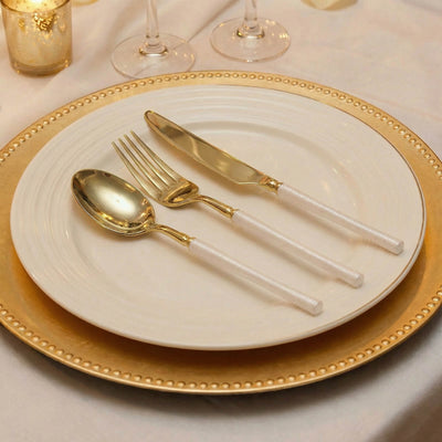 Elegant gold and white table setting with spoon, fork, and knife on a dinner plate
