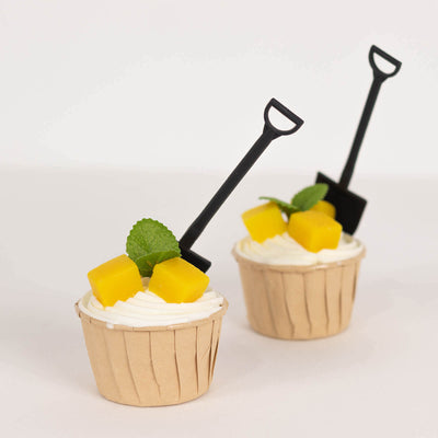 Cupcakes topped with mango and mint, featuring miniature shovels.
