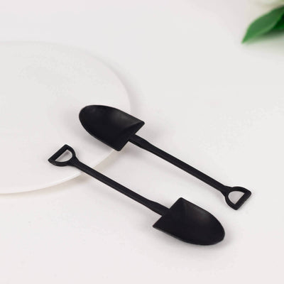 Black mini shovels on a white plate, perfect for gardening or decorative use.