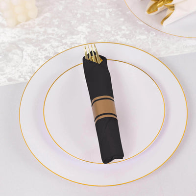 Black napkin with gold band and fork on elegant white plate.