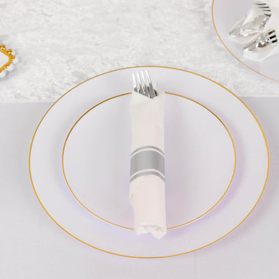 Elegant white dinner plate with gold rim and neatly arranged silverware.