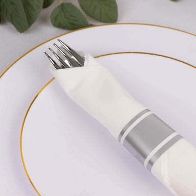 Elegant white napkin with silver band and fork on a decorative plate.