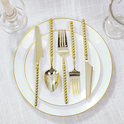 Gold beaded flatware set on white china plate with elegant table setting