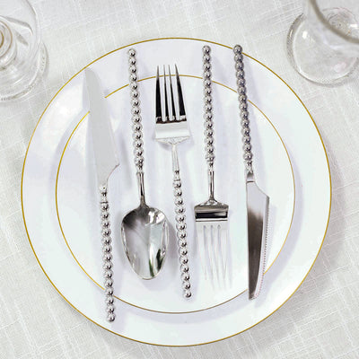 Elegant silver beaded flatware on white gold-rimmed dinner plate
