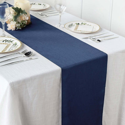 Navy blue table runner on a white table with elegant dining setup.