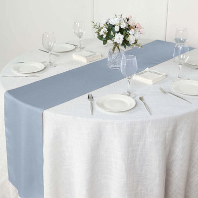 Blue table runner on a white tablecloth with dinnerware and floral centerpiece.
