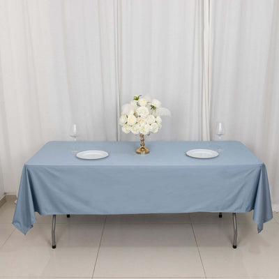 Elegant blue tablecloth with white plates and floral centerpiece on a set table.