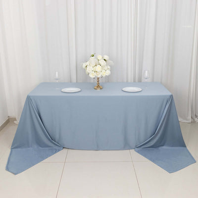 Elegant blue tablecloth with floral centerpiece and dinnerware setup.