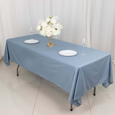 Elegant blue tablecloth set for dining with floral centerpiece and wine glasses.