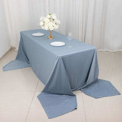Elegant blue tablecloth draped over a table set for dining with flowers.