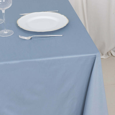 Blue tablecloth with a white plate and cutlery arranged on a table.