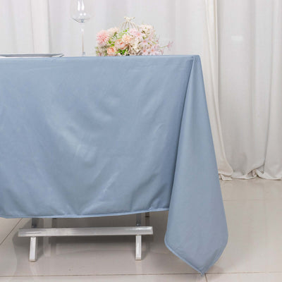 Light blue tablecloth draped elegantly over a table with flowers and glassware.