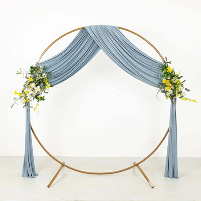 Blue draped wedding arch with floral accents on a white backdrop
