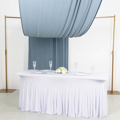 Elegant wedding table setup with draped fabric and floral centerpiece.