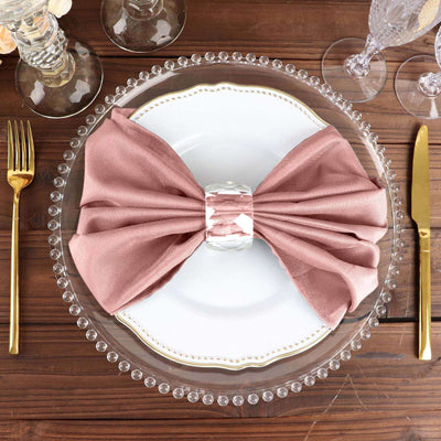 Elegant blush napkin tied with a crystal ring on a decorative plate.