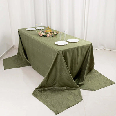 Elegant olive green tablecloth draped over a table with decorative plates and floral centerpiece.