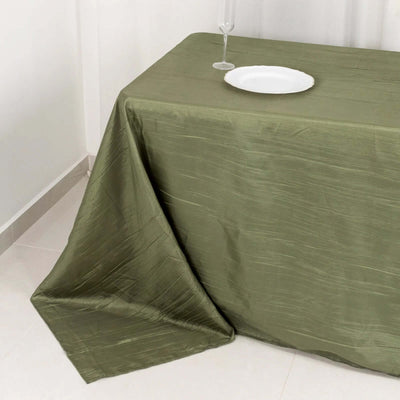 Olive green tablecloth draped on a table with a plate and glass