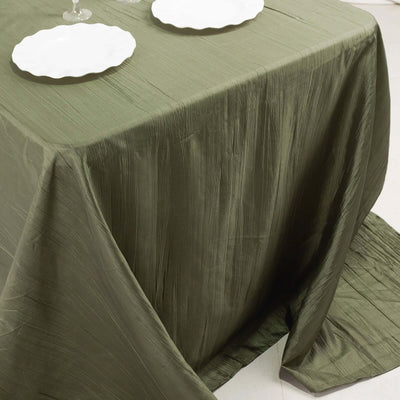 Olive green textured tablecloth draped over a table with white plates