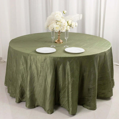 Round olive green tablecloth with plates and floral centerpiece.