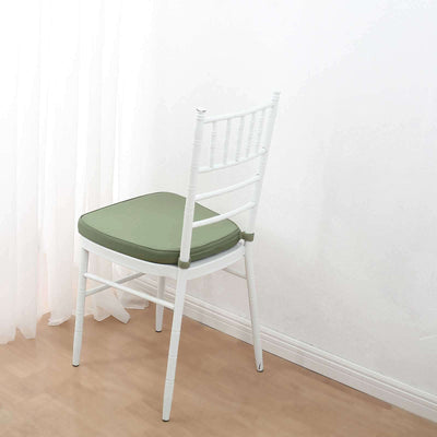 White chair with green cushion on a light wooden floor.