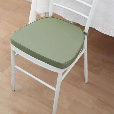 Green chair cushion on a white chair in a minimalistic setting.