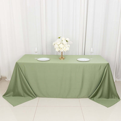 Elegant green tablecloth with floral centerpiece and dinnerware.