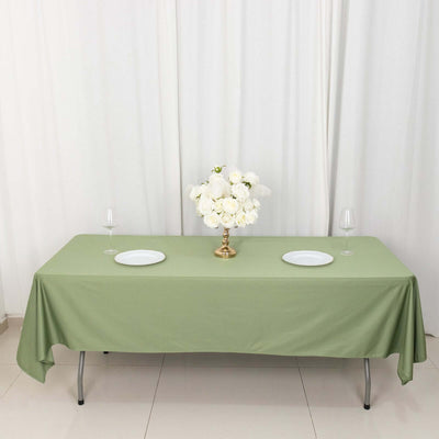 Green tablecloth with white plates and floral centerpiece on a table.
