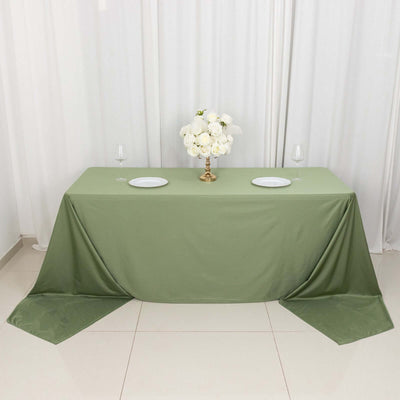 Green tablecloth set up for an elegant dining arrangement with floral centerpiece.