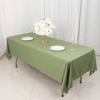 Elegant green tablecloth styled for dining with white plates and floral centerpiece.