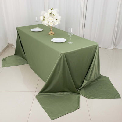 Elegant olive green tablecloth draped on a table with floral centerpiece and dinnerware.