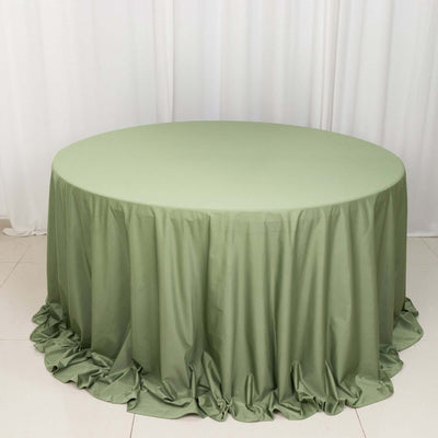 Round olive green tablecloth with ruffled edges on a plain backdrop.