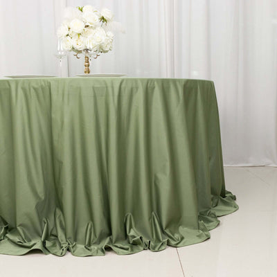 Green tablecloth draped elegantly on a round table with floral centerpiece.