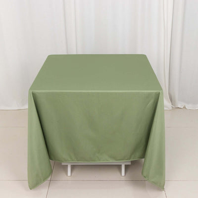Green tablecloth draped over a white table in a studio setting.