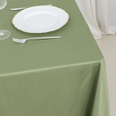Green tablecloth with a white plate and utensils set for dining.