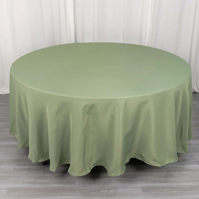 Round olive green tablecloth on a wooden surface.