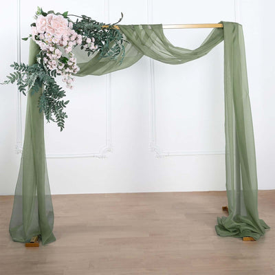 Wedding arch draped with green fabric and pink flowers on a light background.