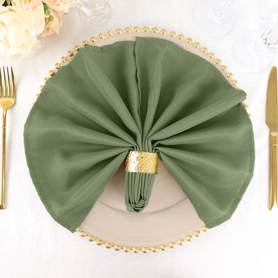 Green napkin elegantly arranged on a plate with a gold napkin ring.