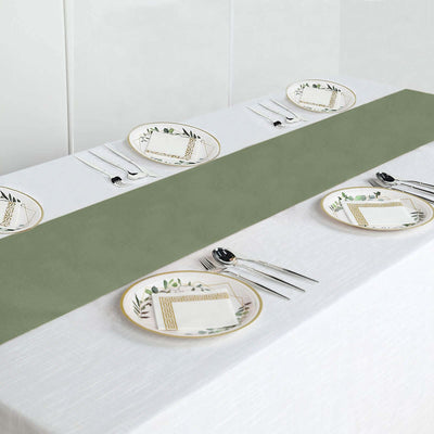 Elegant green table runner on a white table with decorative plates and cutlery.