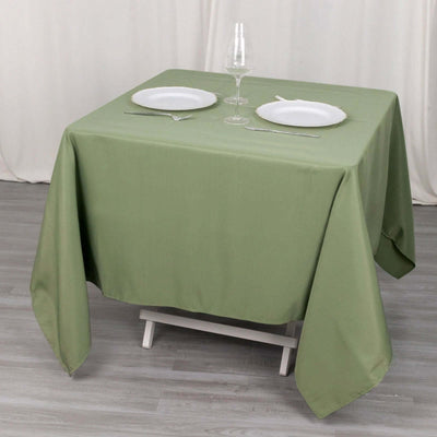 Green tablecloth draped over a table set for two with plates and glassware.